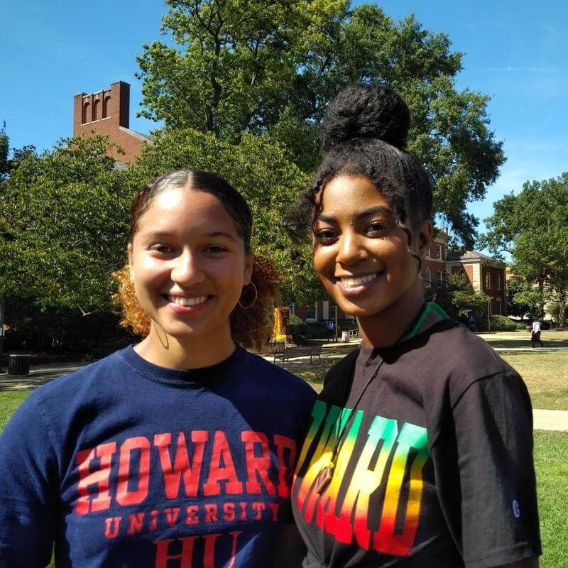 Two female environmental students are on the Yard, wearing Howard tee shirts and smiling at the camera. 