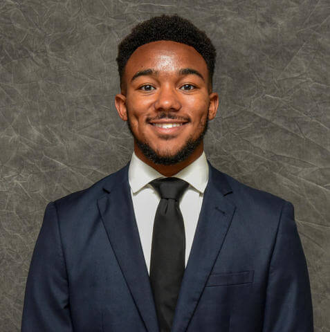 Danurius Williams is dressed in a suit and tie. He looks into the camera and smiles.